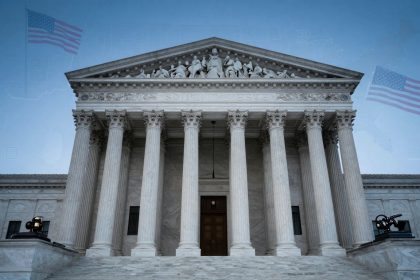 The image shows the front facade of the U.S. Supreme Court building with its iconic columns and sculpted pediment. Two American flags are superimposed in the sky above. A large gavel is visible on a pedestal in the foreground. The sky is clear and blue.