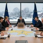 Seven people in suits sit around a conference table with a map in the center. Flags of the EU and USA are visible. A snowy scene is outside the window.