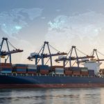 A large cargo ship loaded with multicolored shipping containers is docked at a port with cranes. A world map overlay is visible in the sky.