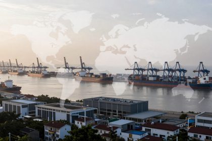 Aerial view of a busy port with multiple cargo ships docked at piers, cranes visible above. In the foreground, a cityscape with modern buildings. A translucent world map overlays the scene.