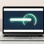 A laptop displaying a digital speedometer on its screen, with a glowing green needle pointing to 70. The background shows blurred city buildings.