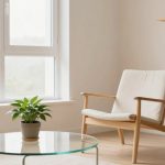 A minimalist room with a light wooden chair and white cushion, a glass coffee table with a potted plant, large window, and shelf with decor.