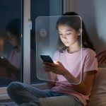 A girl in a pink shirt sits on a bed, looking at her smartphone. A translucent screen with app icons overlays her. A hand reaches toward her.