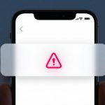 Smartphone screen displaying a red warning triangle with an exclamation mark. Blurred cityscape and padlock icons in the background.