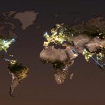 World map depicting continents at night with illuminated city lights. Bright clusters are visible in North America, Europe, and Asia, with some connecting lines.