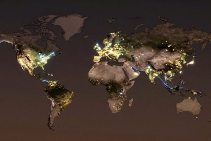 World map depicting continents at night with illuminated city lights. Bright clusters are visible in North America, Europe, and Asia, with some connecting lines.