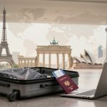 Open suitcase with clothes, a passport, and boarding pass next to a laptop on a shiny floor. Background features iconic landmarks like the Eiffel Tower and Sydney Opera House.